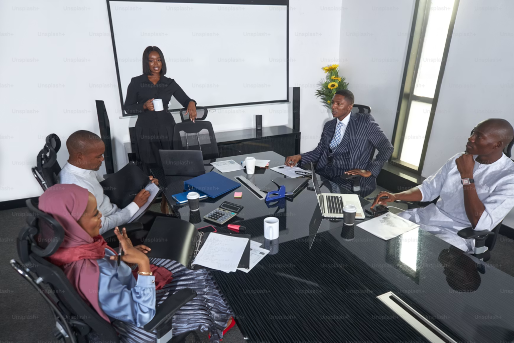 Nigerian colleagues in a modern office environment, some wearing traditional Ankara attire alongside Western dress